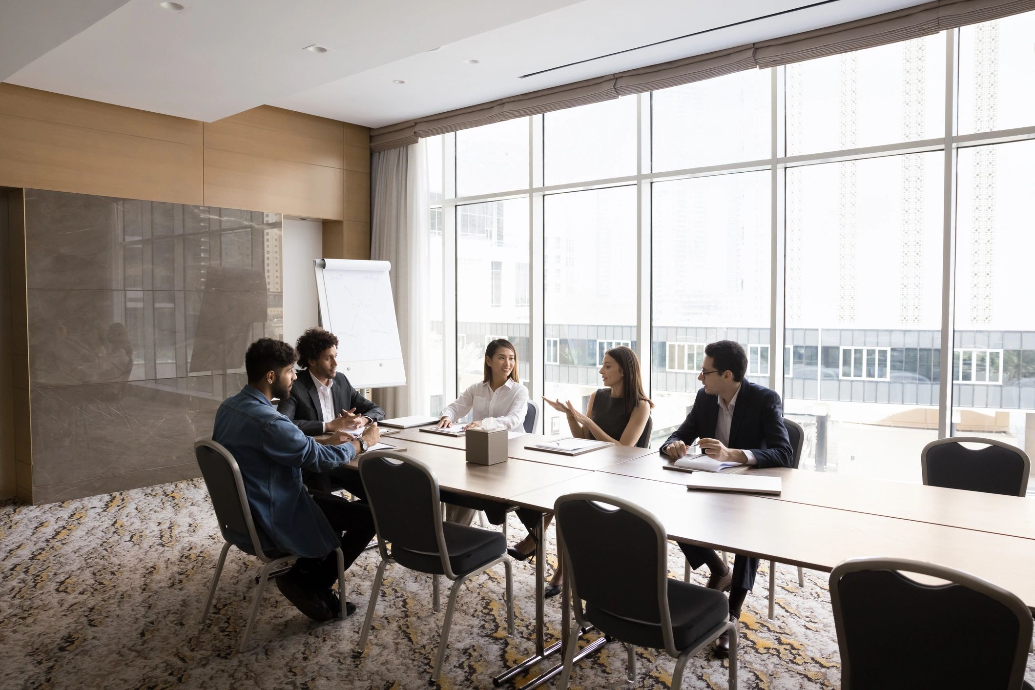 Positive multiethnic team of project managers talking at large table